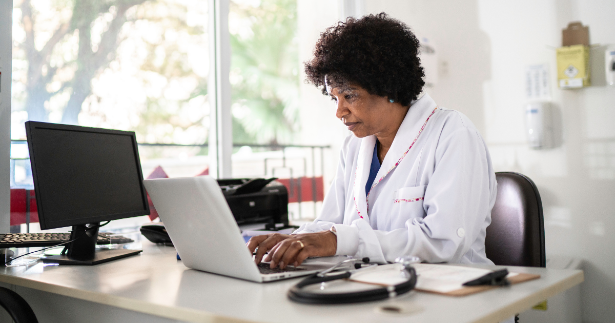 A female doctor is reading emails on her laptop.